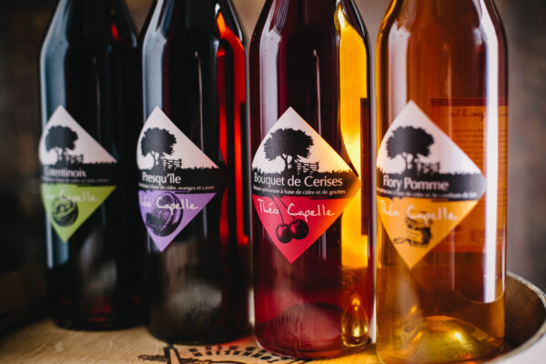 Bouteilles de cidre de la Cidrerie Théo Capelle, dont le Bouquet de Cerises, avec des étiquettes colorées.