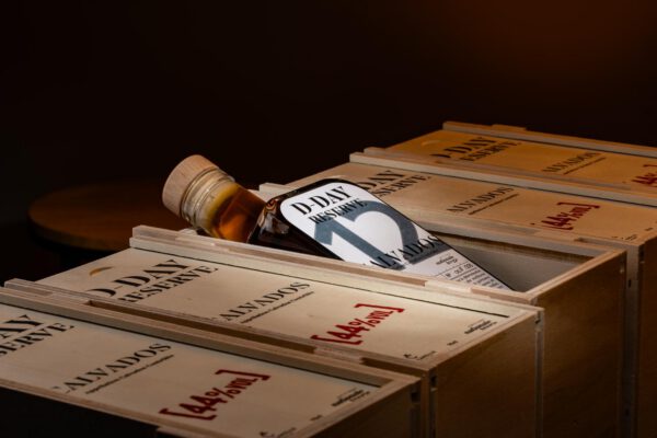 Bouteille de Calvados D DAY Réserve 12 ans, présentée dans une boîte en bois, mettant en avant l'artisanat normand.