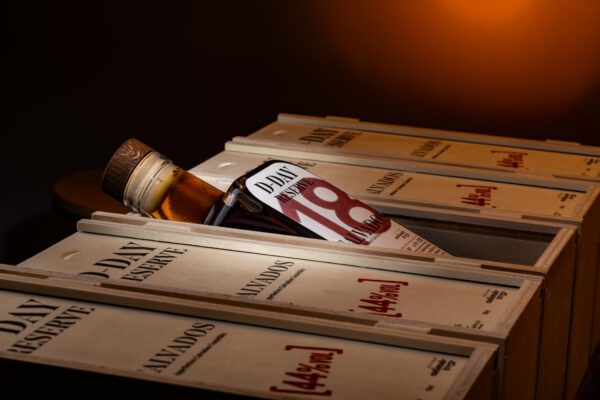 Bouteille de Calvados D Day Réserve 18 ans, en bois, présentée sur un fond sombre.
