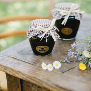 Bocal de pruneaux au calvados de 580 ml, sur une table en bois avec des fleurs.