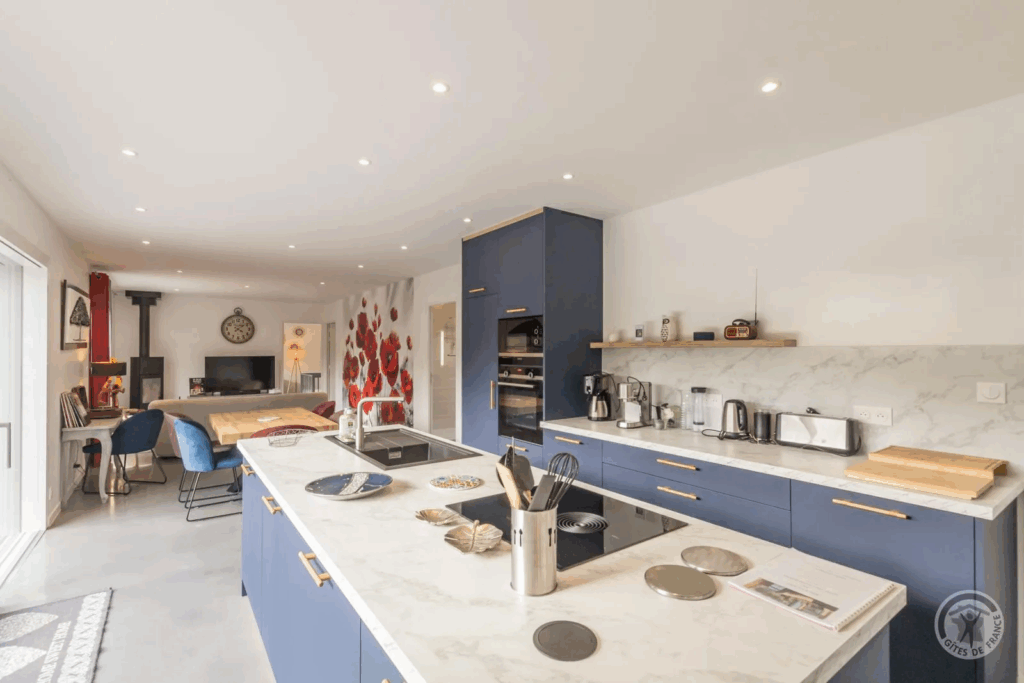 Le gîte - Cuisine moderne avec îlot central, équipements en inox et décoration chaleureuse à la Cidrerie-Distillerie Théo Capelle.