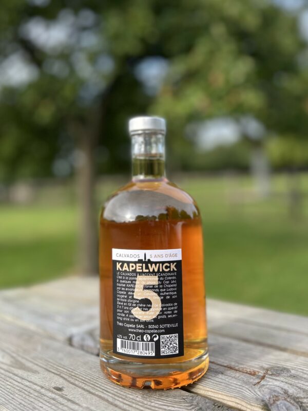 Bouteille de Calvados Kapelwick 5 ans d'âge, 50 cl, sur fond naturel, mettant en valeur son étiquette et sa couleur ambrée.