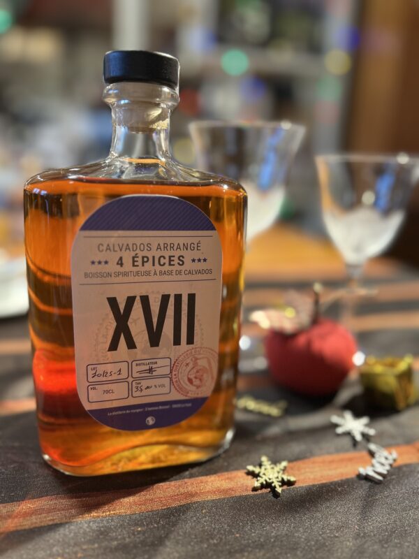 Bouteille de Calvados arrangé 4 épices, distillerie Théo Capelle, sur une table décorée.